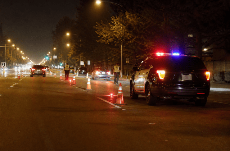 Nighttime DUI checkpoint with traffic cones and a patrol vehicle
