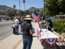 Volunteers at an outdoor table with American flags and clipboards