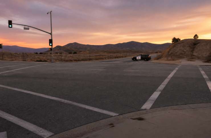 Empty intersection at dusk with a patrol vehicle in the distance